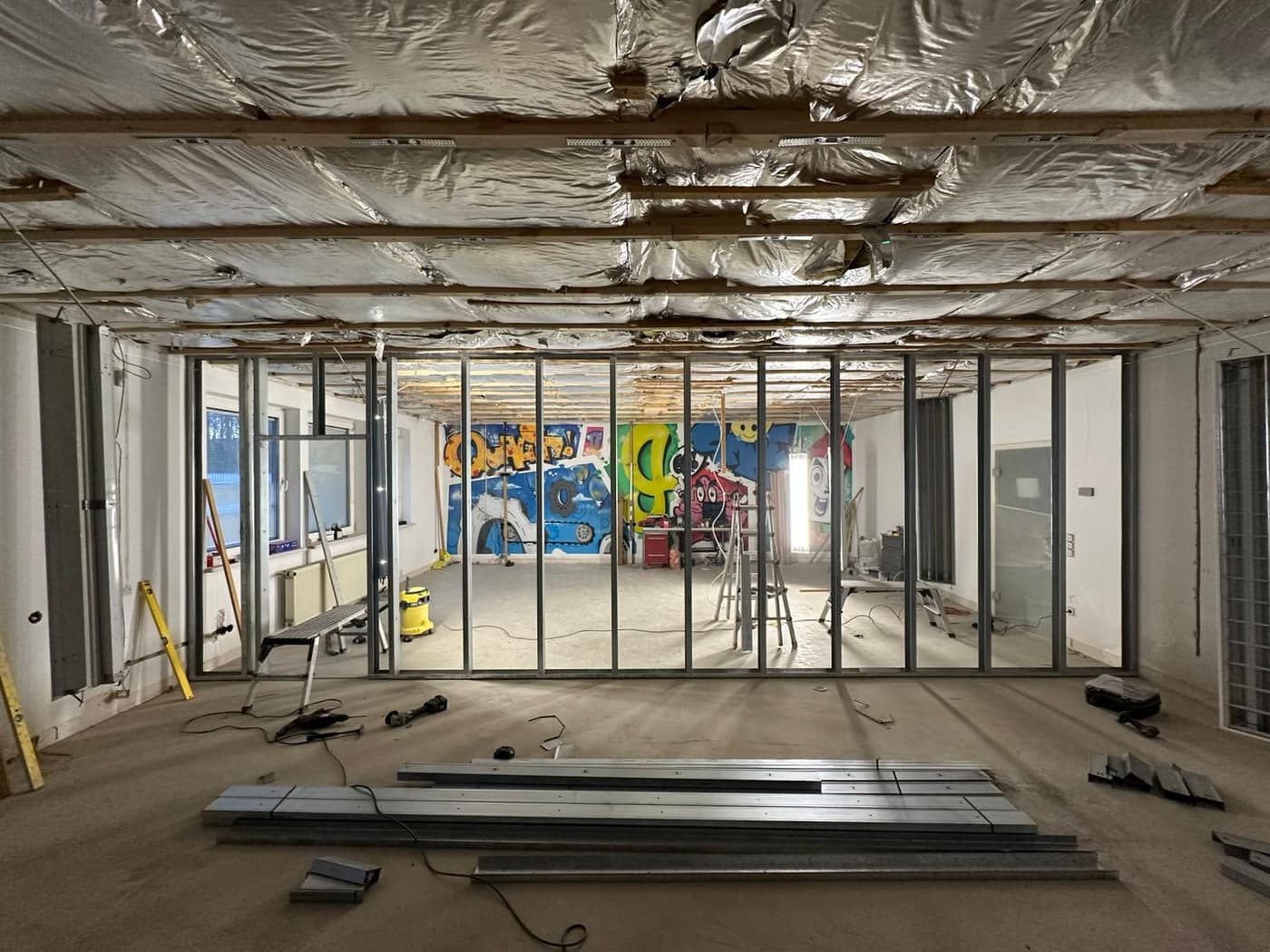 Neue Trennwände im Ständerwerk, dahinter eine bemalte Wand